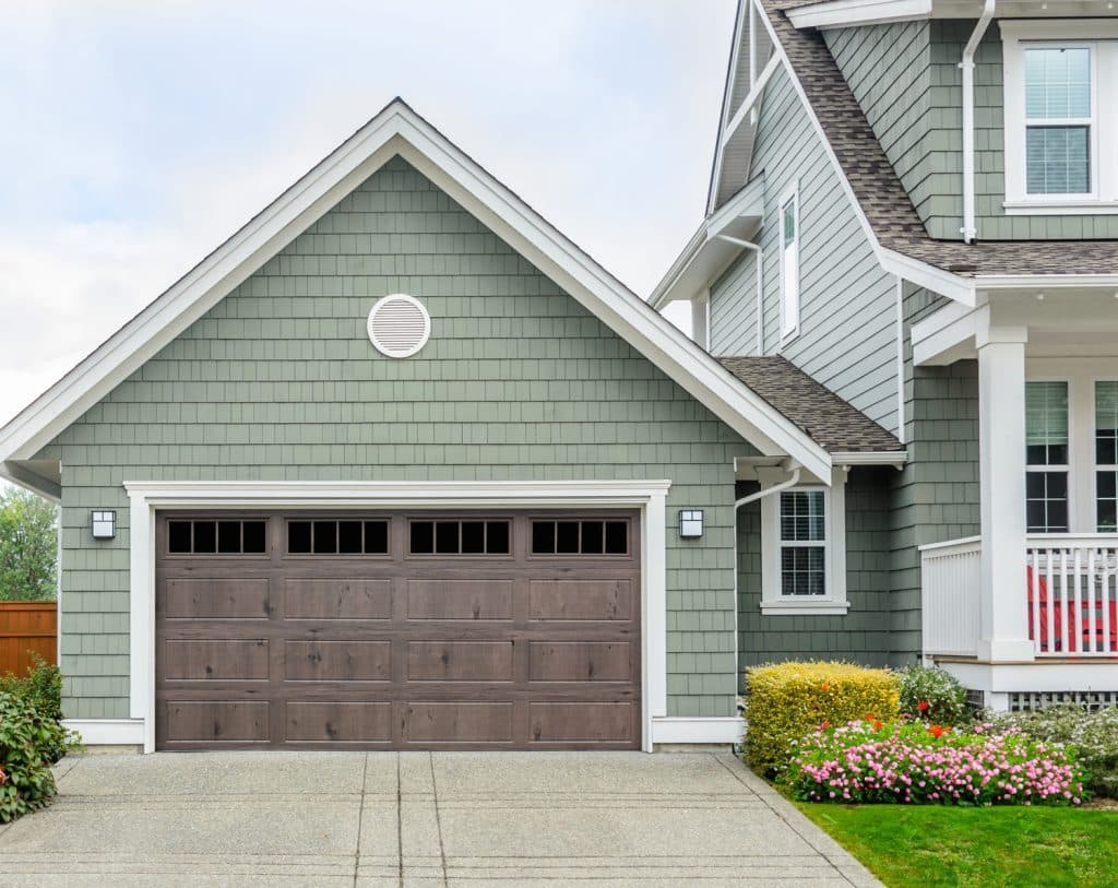 Bi-Directional wood grain garage door in Classic on a green cottage