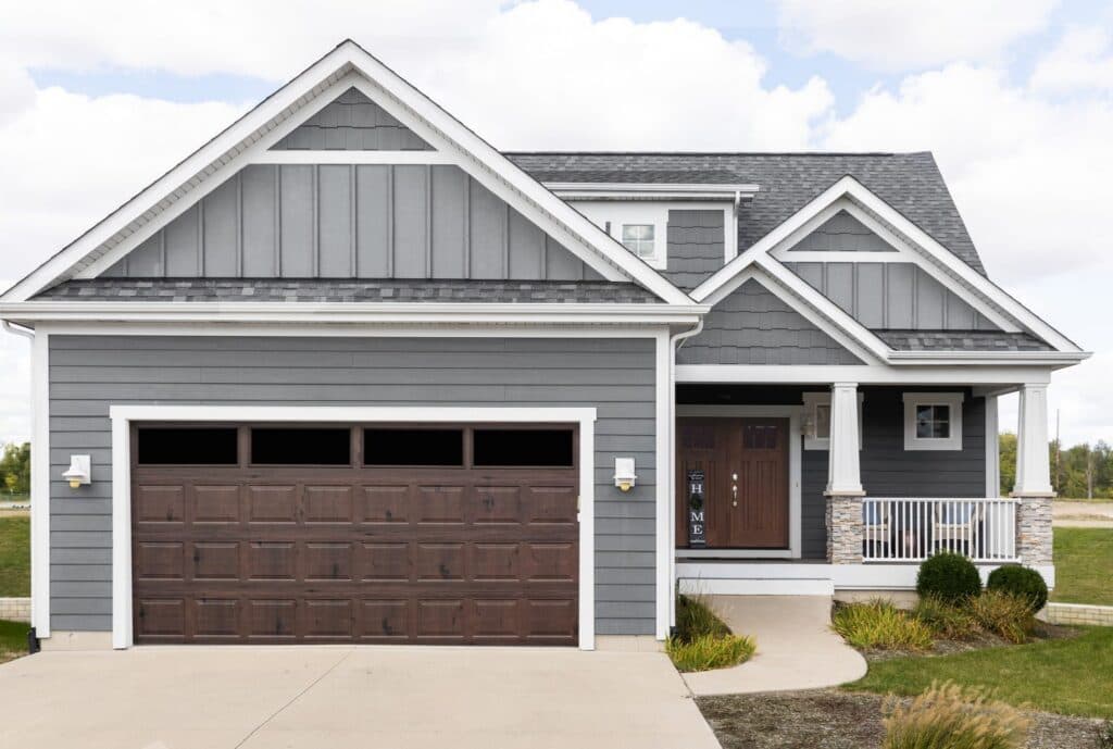 Bi-Directional wood grain garage door in Walnut on a grey home