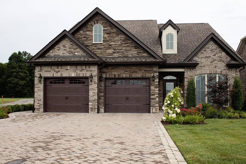 Carriage-style Ankmar garage doors on a stone and brick home