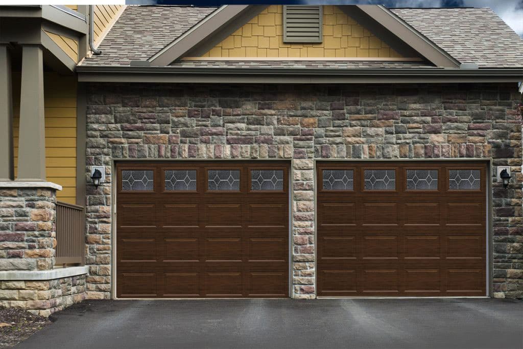 Madera Series wood-grain garage doors on a stone and stucco home in Pueblo