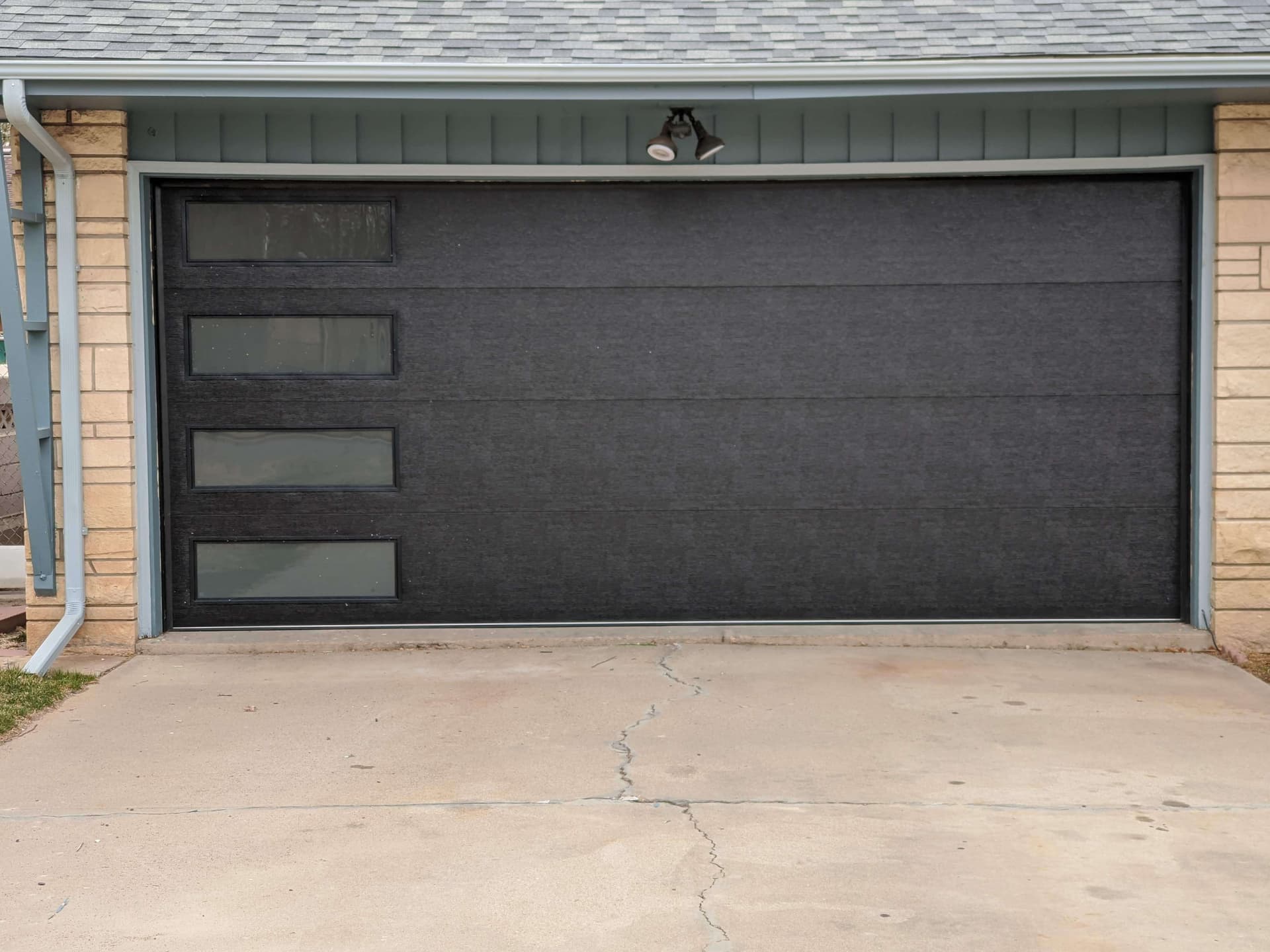 Modern black flush-panel garage door installed on a Pueblo home